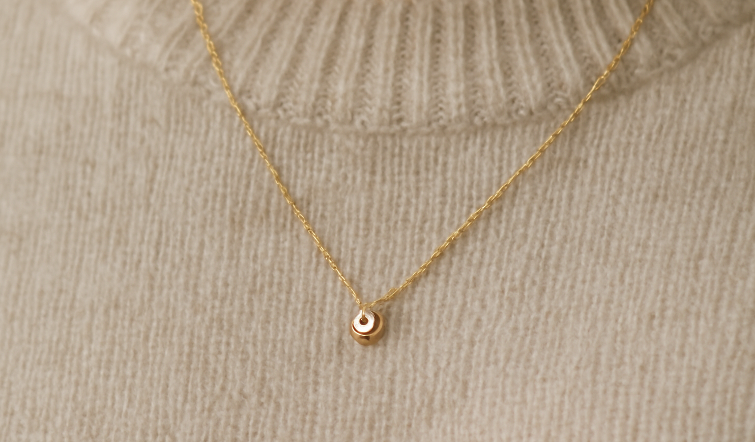 collier delicat pose sur un pull neutre