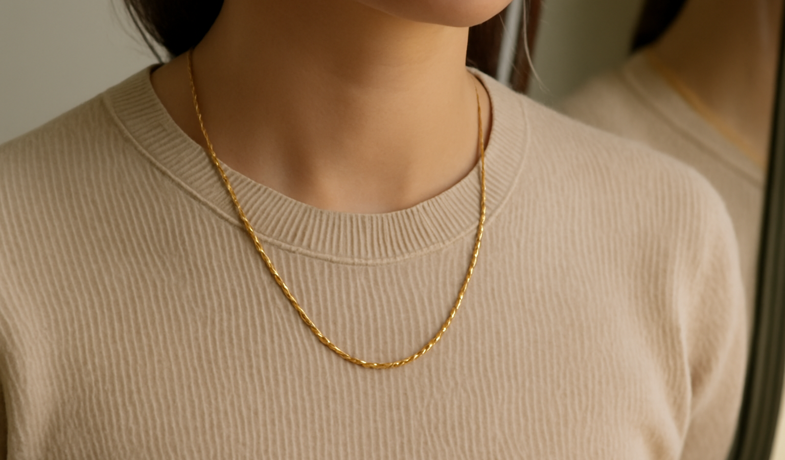 collier porté sur pull uni devant miroir